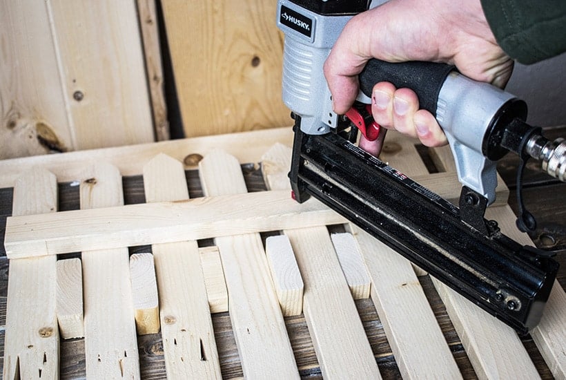 Using a nail gun to attach the top rail to the pickets.