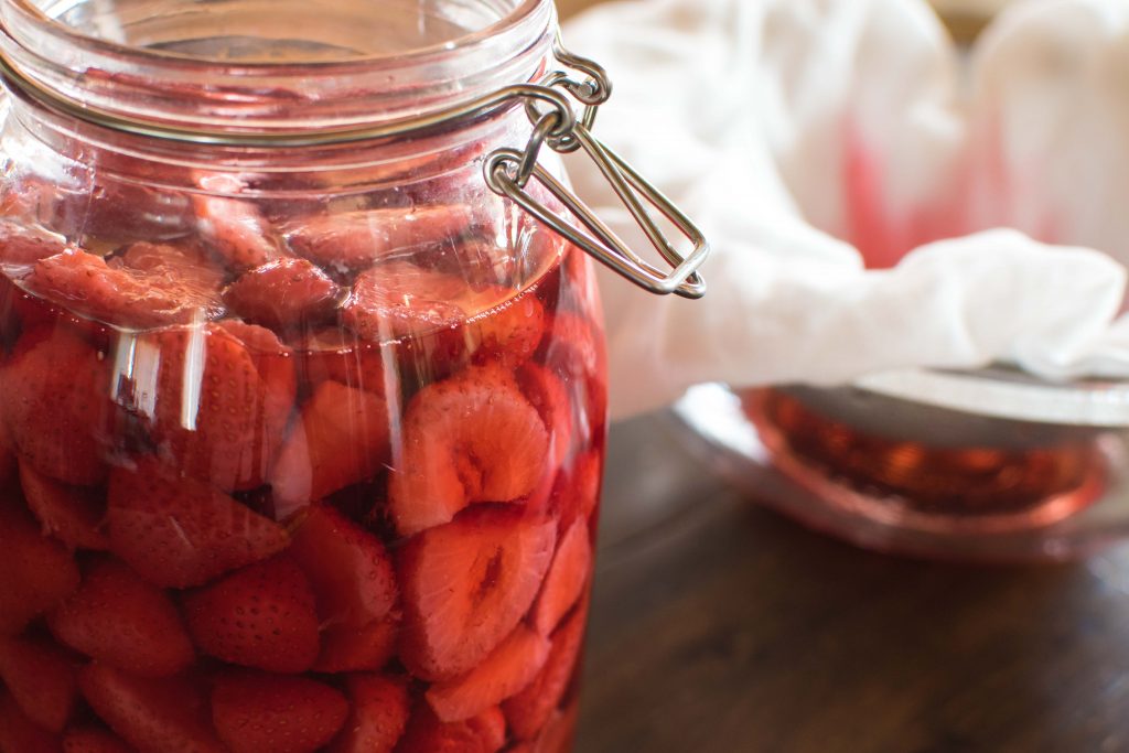 strawberries and vodka in a large mason jar