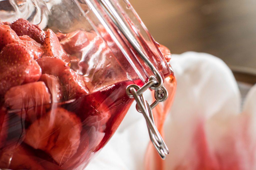 strawberry infused vodka being poured from a mason jar