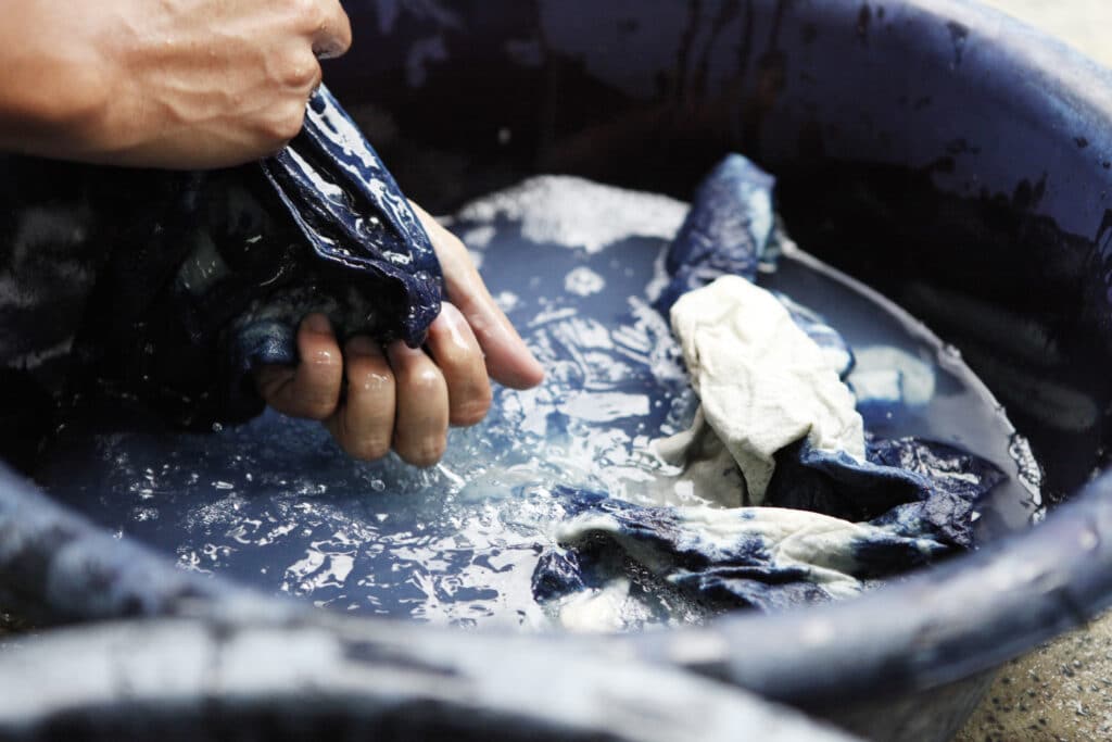Fabric being soaked in natural blue fabric dye from plants.