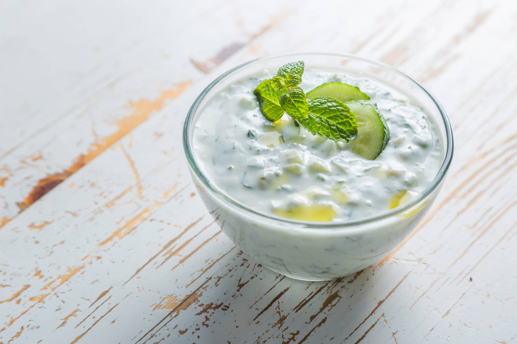 Tzatziki in a bowl garnished with sliced cucumber.