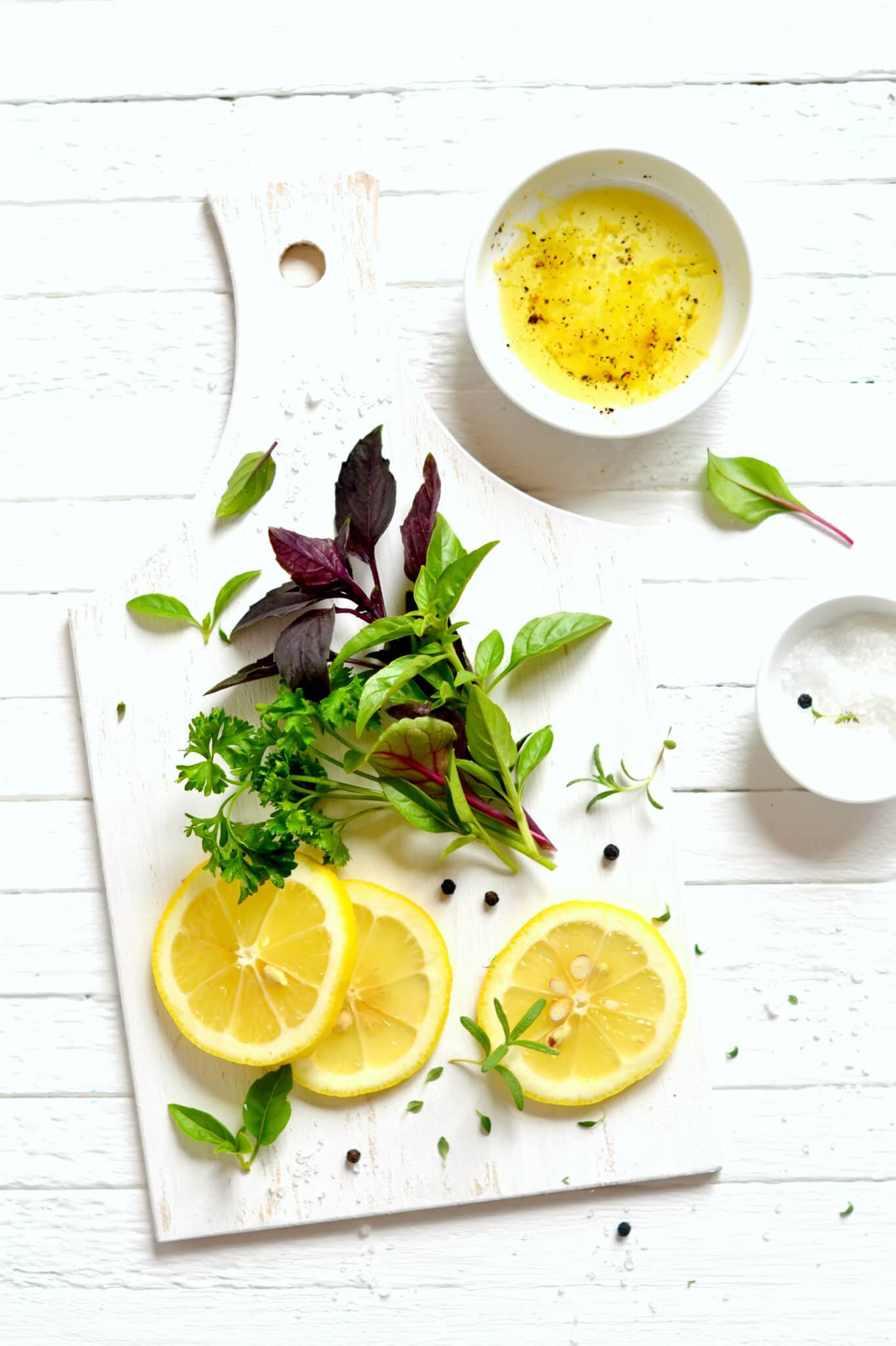 fresh garden herbs and lemon on a white surface