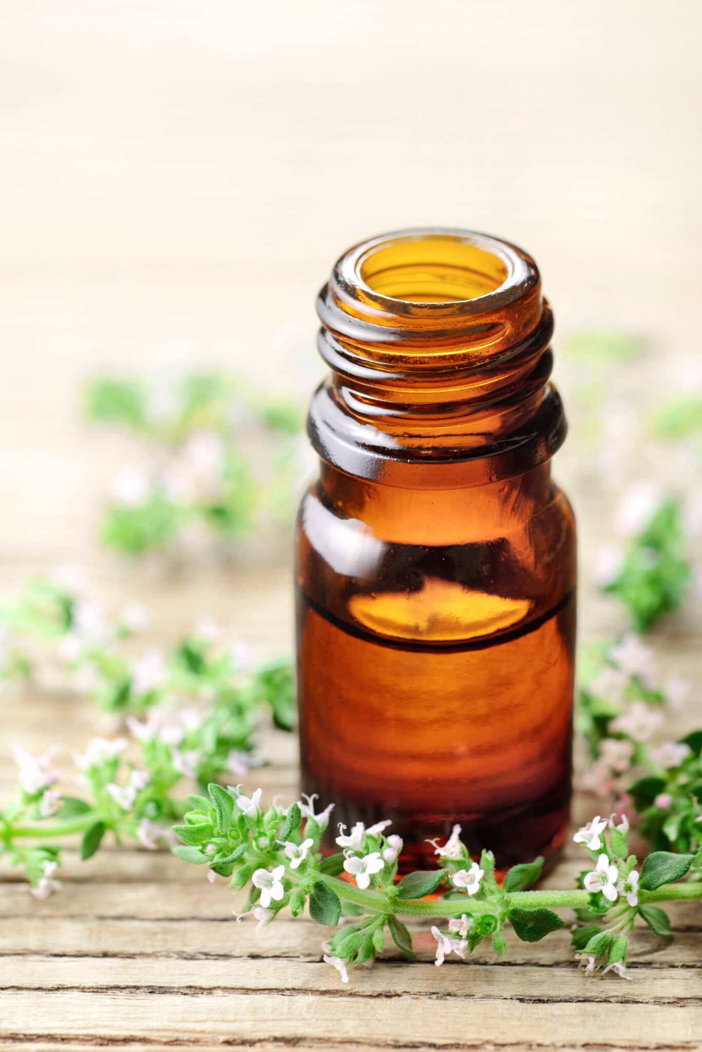 A glass essential oil bottle on a woos table.