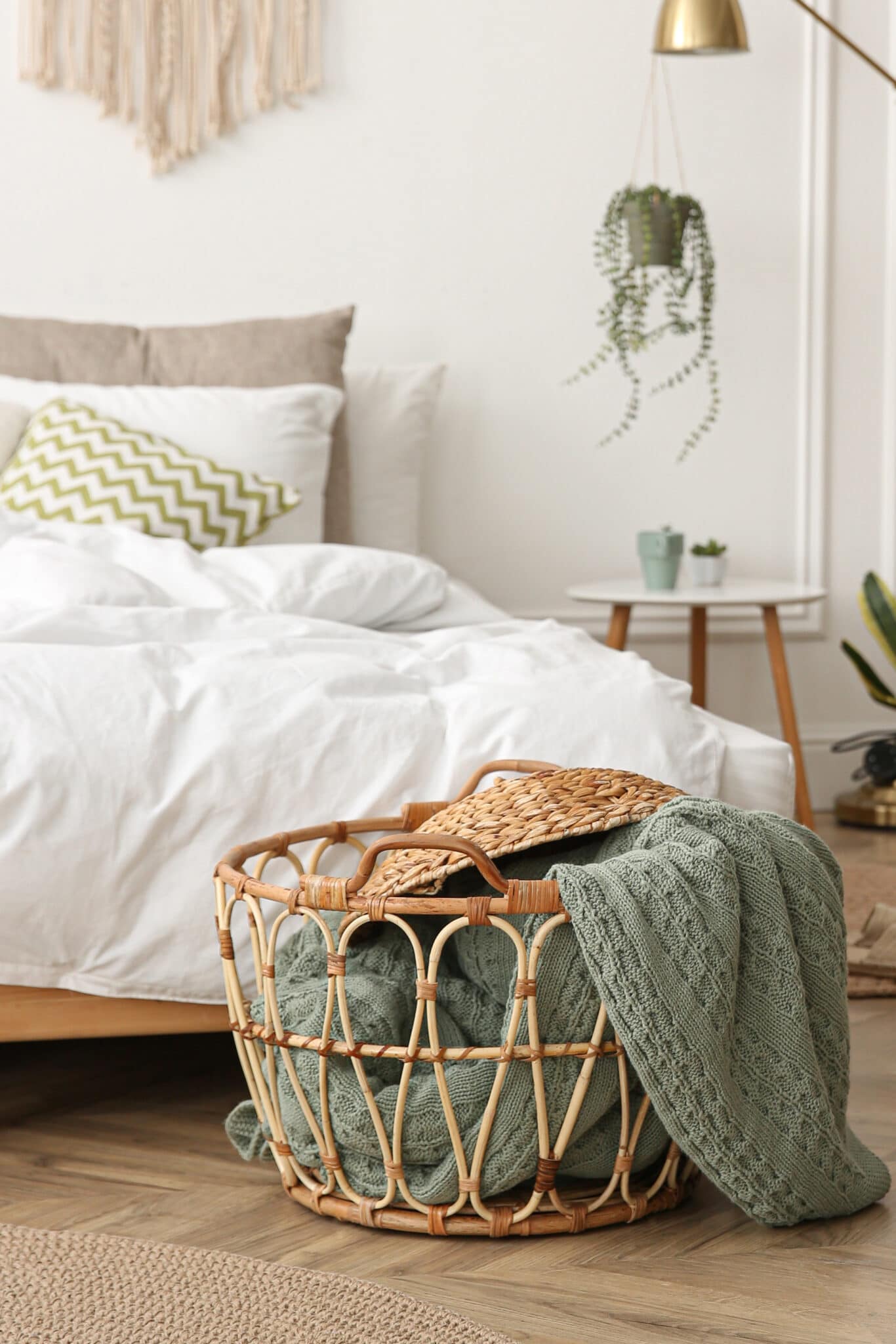 A wicker basket being used to store blankets in a bedroom.
