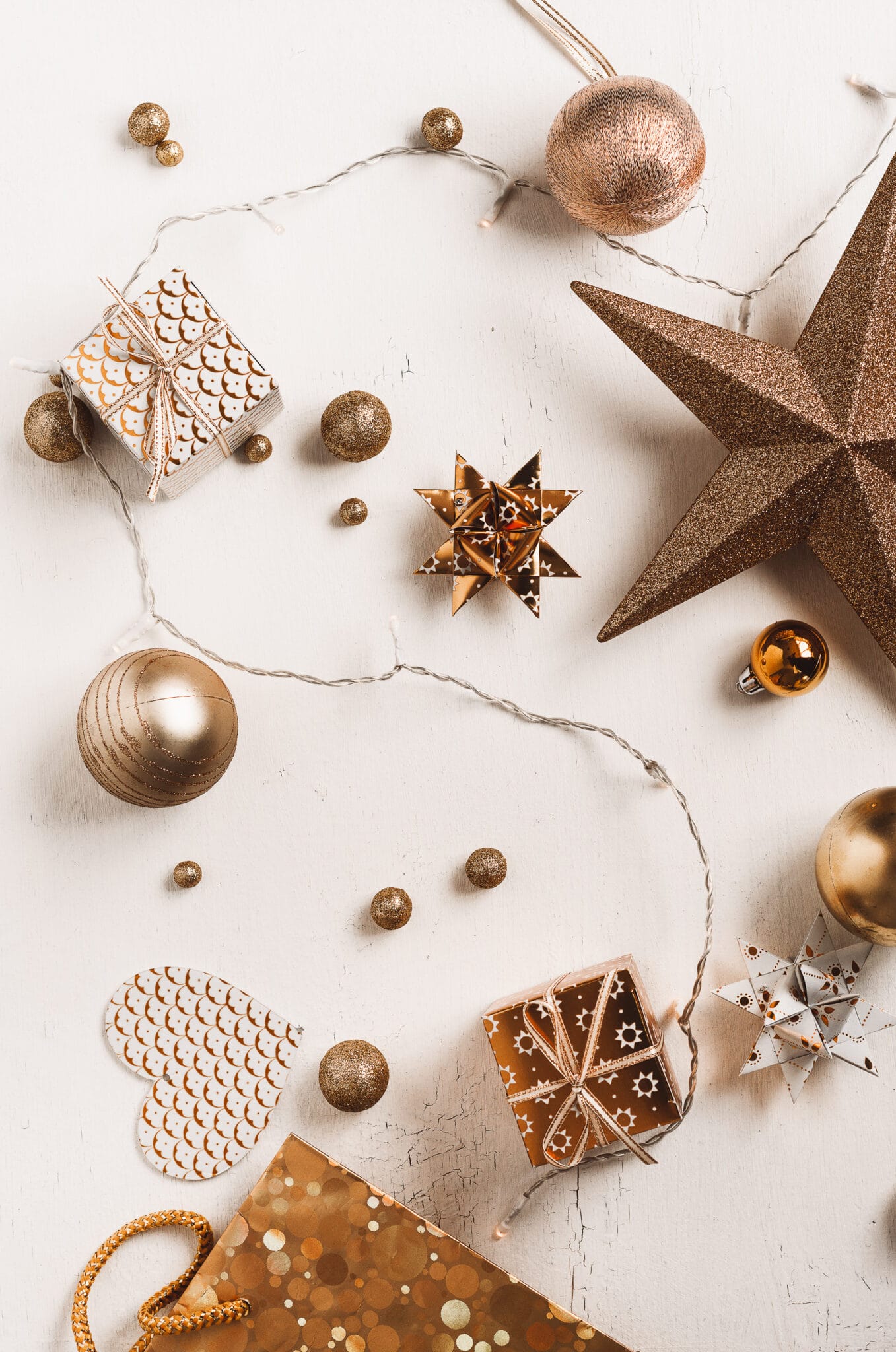 Organizing christmas ornaments by gold color.  Ornaments are scattered across a white rustic tabletop. 