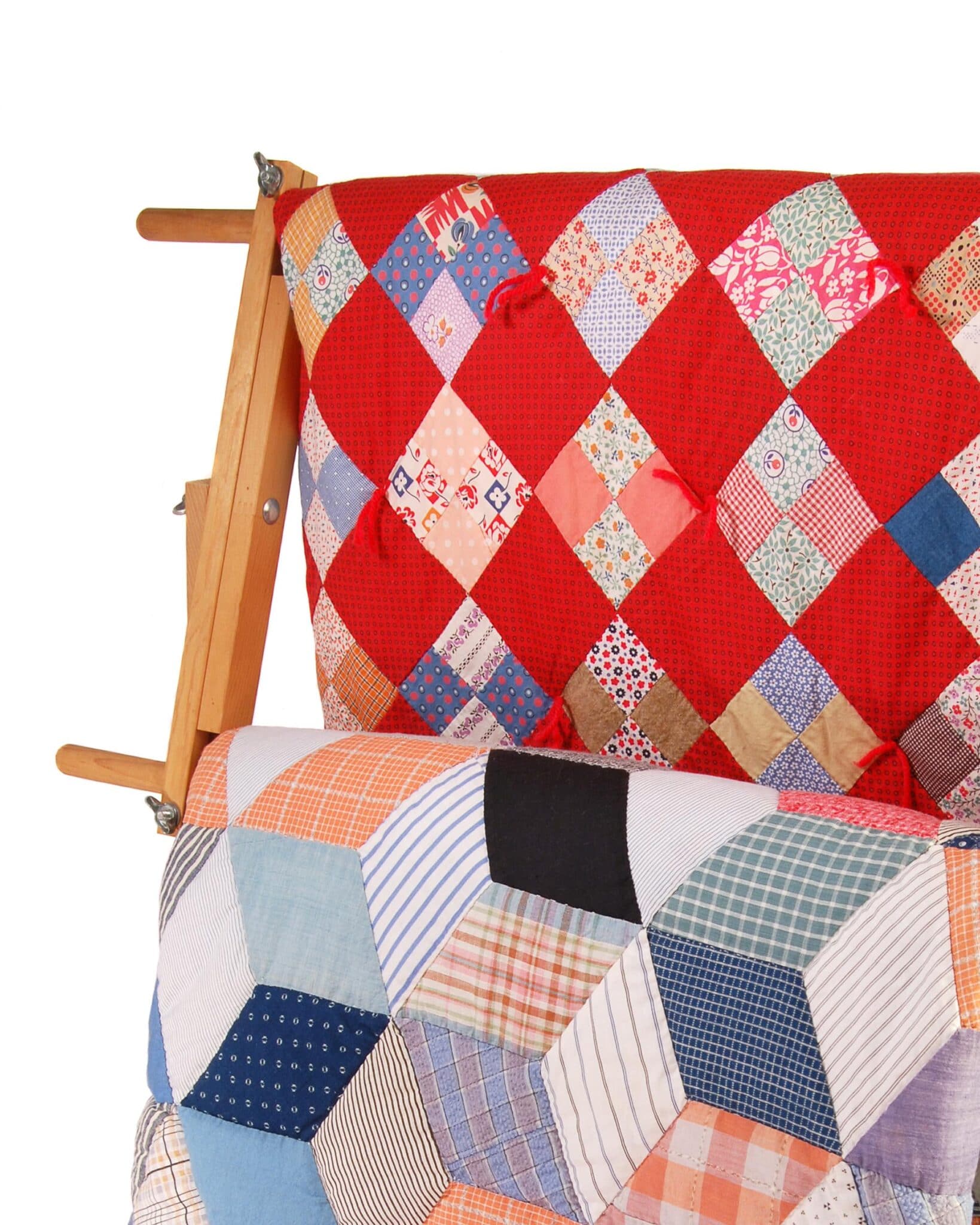 Detail view of two multicolor quilts hanging on a wooden display rack..