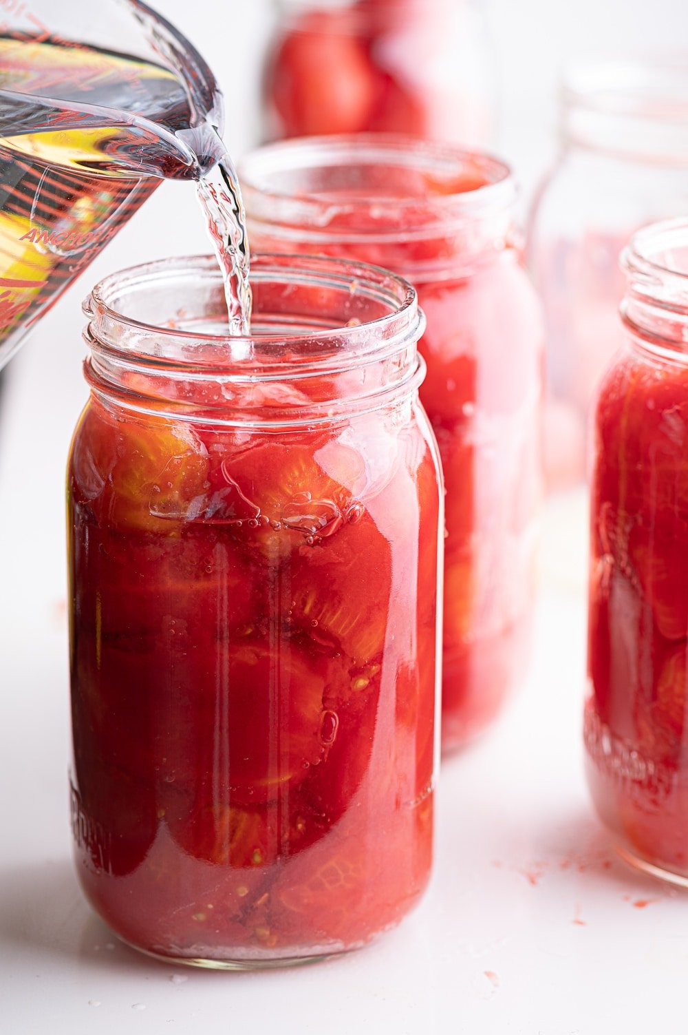 Topping up canned whole tomatoes with fresh water.