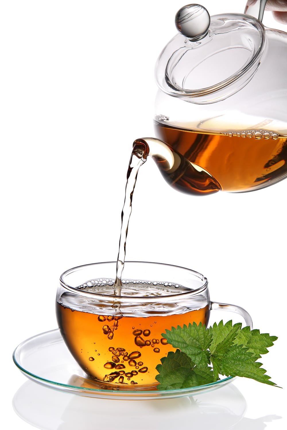 Fresh hot tea being poured into a teacup.