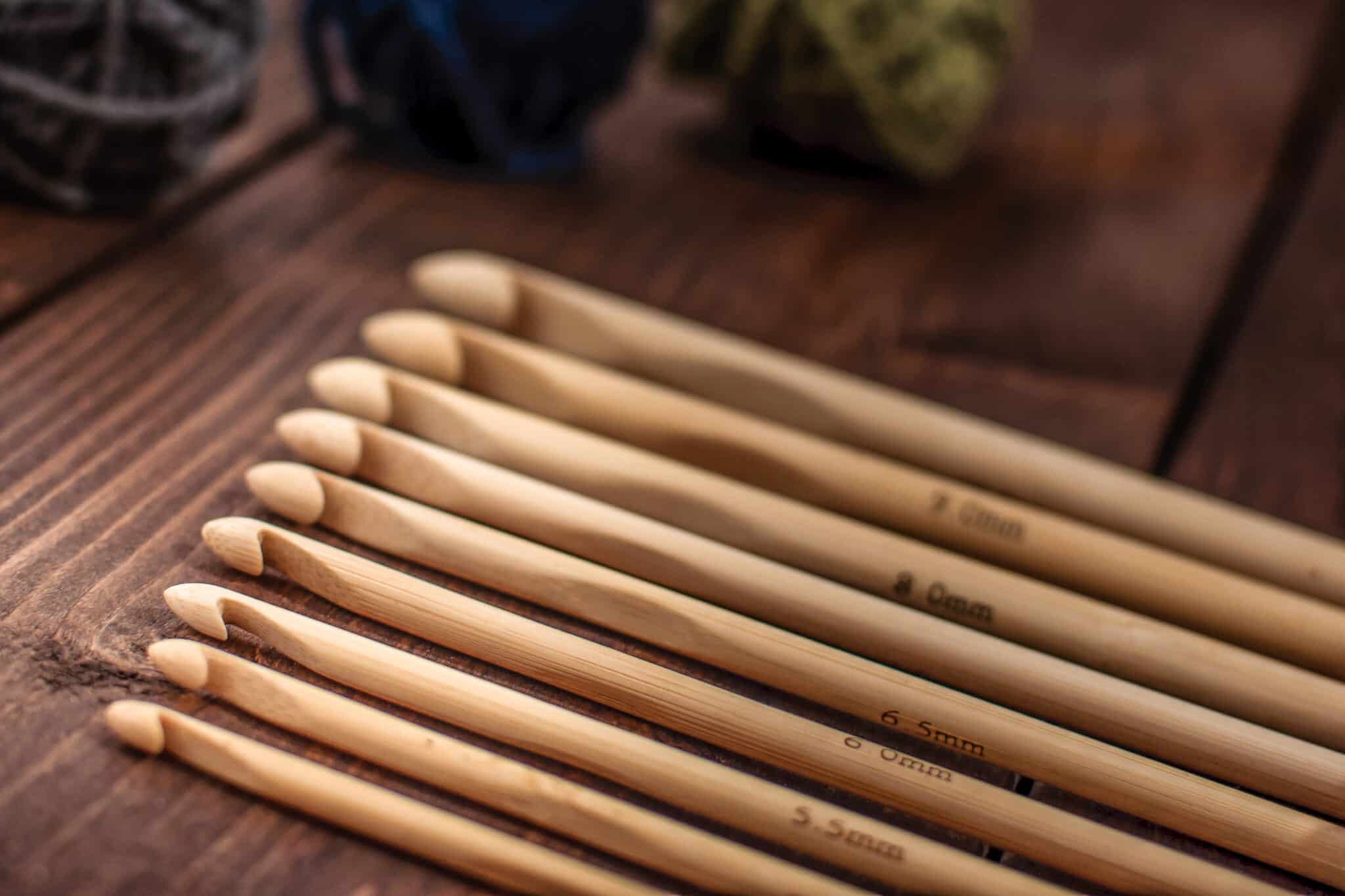 Bamboo crochet hooks in different sizes on a rustic wooden tabletop.