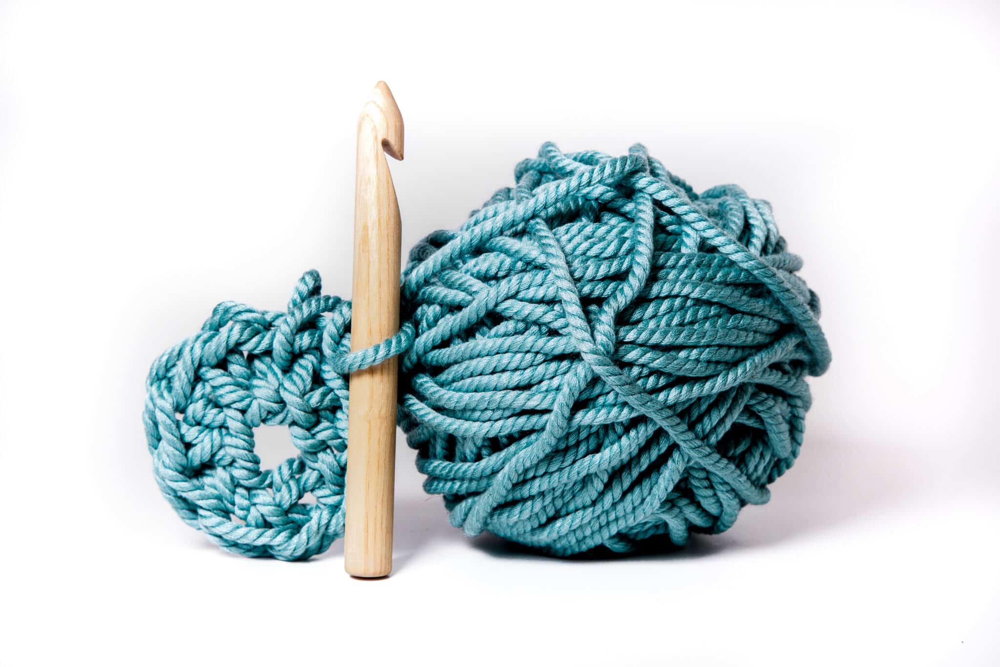 A ball of yarn, with a large crochet hook looped into an in-progress project.