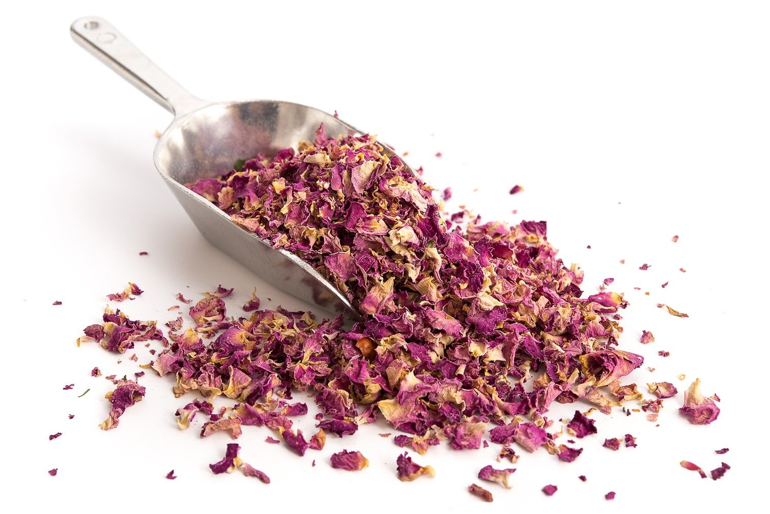 Dried rose petals on a metal scoop against a bright white background.